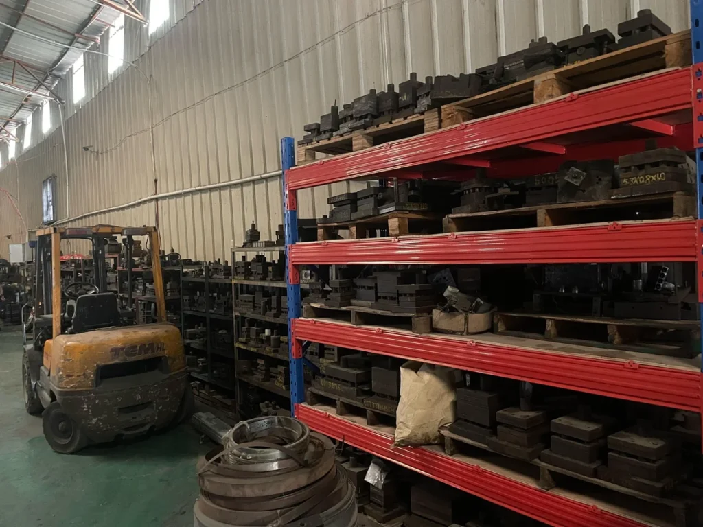 Rows of stamping dies stored on industrial shelving in factory warehouse