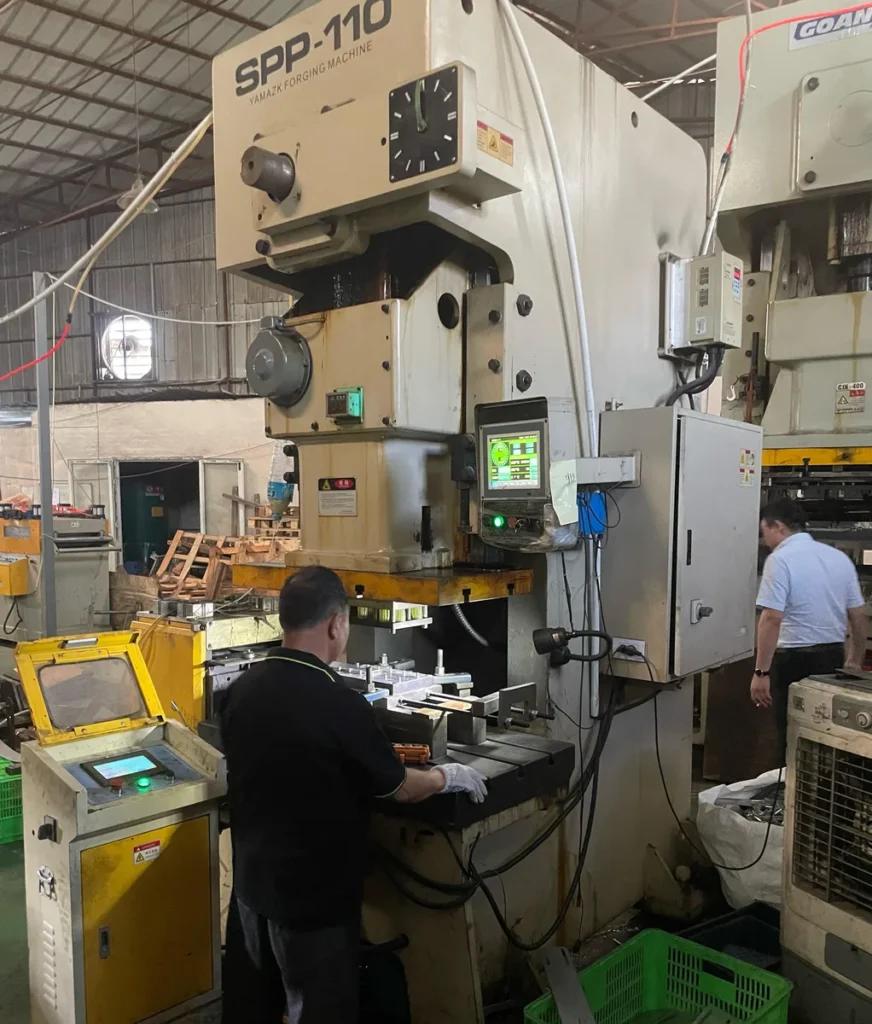 Worker operating YAMAZK SPP-110 metal stamping press Metal Stamp Factory