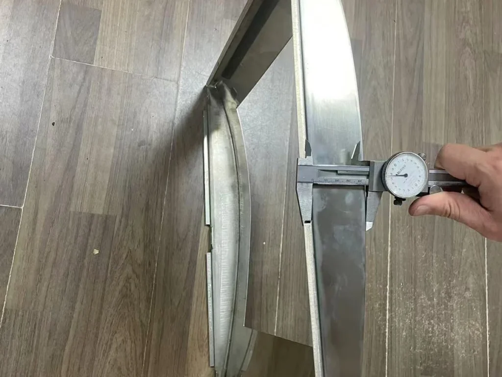 Side profile of stainless steel panel being measured with dial caliper after CNC press-brake bending