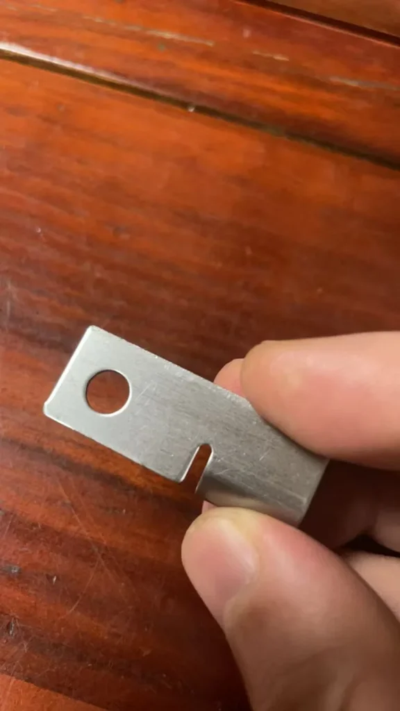 Stamped stainless steel part showing die clearance and edge burr