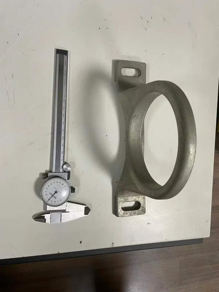 deep drawn heavy-duty truck bearing housing back view, next to caliper for scale