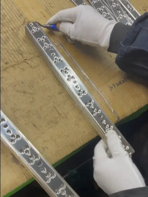 Worker manually deburring a SUS304 stainless steel bird spike base with a handheld scraper